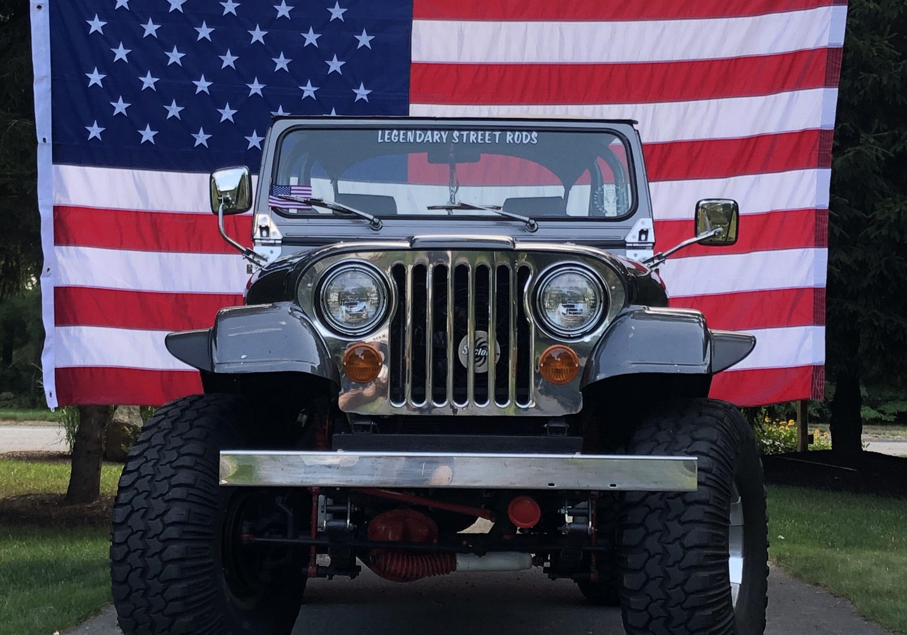 Classic Jeep parked in front of American flag